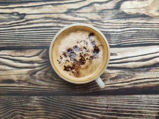 A fresh cup of coffee with cocoa granule as topping. The combination of strong coffee, creamy flavor, smooth foam, and crunchy choco granule. Top view. Flat lay.