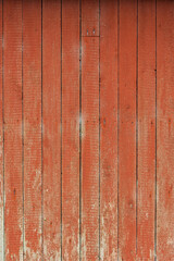 Textured red wooden wall displays wear and natural patterns, reflecting years of use in a quiet countryside environment.