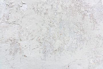 A textured white wall shows signs of wear with cracks and imperfections, illuminated by soft natural light in a minimalist environment.