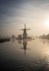 Dutch Windmill Reflected in Calm Water at Sunrise.