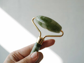 Close-up woman hand holding jade stone jade roller for skincare wellness beauty facial massage and natural rejuvenation
