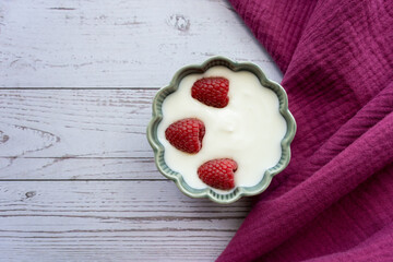 Green porcelain bowl and natural yogurt with berries on the wood table.