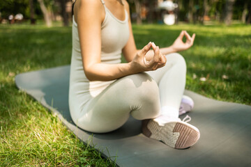 Young woman practicing yoga in the park. Concept of healthy lifestyle and relaxation.