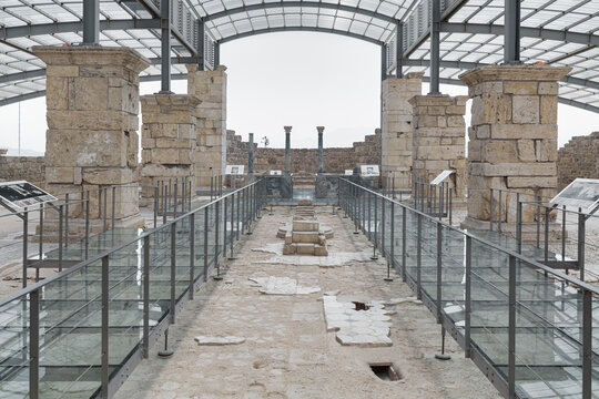 Monochrome view of Church of the Apocalypse ruins in Laodicea, Turkey, with preserved columns and glass walkway under canopy