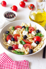 Pasta salad with farfalle, tomatoes, cheese, olives and basil. Italian cuisine. Vegetarian food.