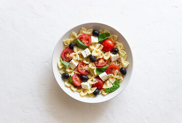 Pasta salad with farfalle, tomatoes, cheese, olives and basil. Italian cuisine. Vegetarian food.