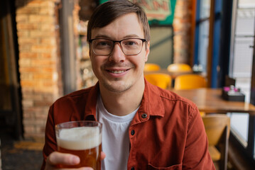 Happy customer enjoying a refreshing pint of beer in a cozy pub, showcasing the friendly atmosphere and the simple pleasure of a cold beverage