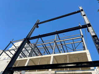 Steel frame structure of modern building under construction against blue sky - useful for architecture, engineering, construction industry, urban development, and structural design visuals
