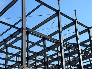 Steel frame structure of modern building under construction against blue sky - useful for architecture, engineering, construction industry, urban development, and structural design visuals