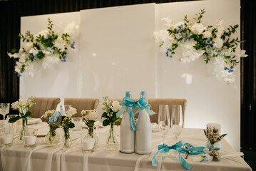 The interior of the restaurant is decorated with fresh flowers for a wedding celebration, decorated with a white screen and a banquet table with food and drinks covered with a white tablecloth