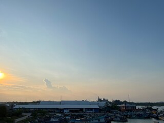 A serene sunset over a harbor with boats and buildings silhouetted against the sky.