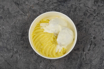 mashed potatoes with meatballs in a creamy sauce in a disposable plate on a gray background