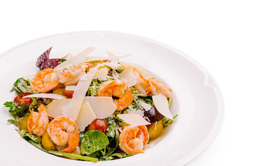 Colorful shrimp salad with greens, tomatoes, and cheese served on white plate