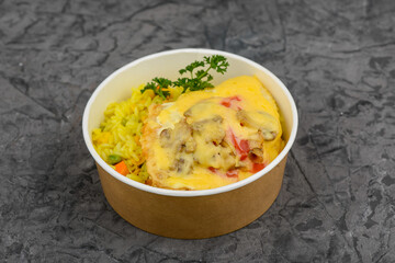 rice with vegetables and omelet with vegetables in a disposable plate on a gray concrete background