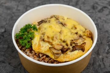 buckwheat porridge with meat chop and cheese in a disposable plate