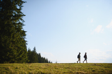 Fototapeta premium Hikers walking on a trail near a forest on sunny summer day