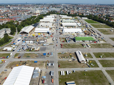 Munich, Germany - 18 August 2025: Aerial view of the Messe M&Atilde;&frac14;nchen exhibition grounds, a vibrant tapestry of white tents and colorful structures against a backdrop of the city's skyline.