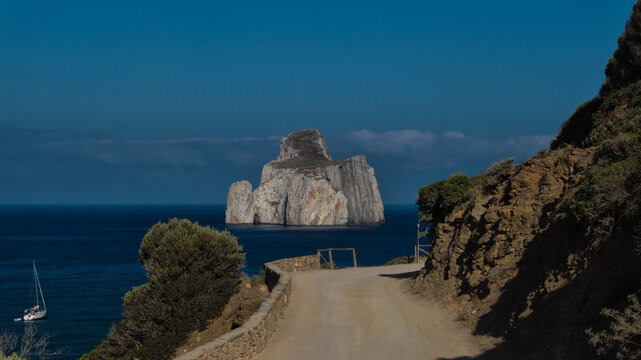 Aerial view of the imposing Pan di Zucchero rock formation rising from the turquoise sea, framed by the rugged coastline, Masua, Sardinia, Italy.