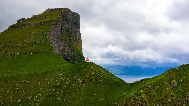 Aerial view of the iconic Kallur Lighthouse perched atop a verdant hill against the dramatic cliffs and moody skies, Tr&Atilde;&cedil;llanes, Nor&Atilde;&deg;oya, Faroe Islands.