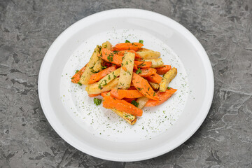 fried potatoes with carrots in spices in a white plate on a gray background