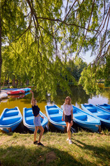 Fototapeta premium Two middle-aged sisters spending a summer morning in the park by a lake relaxing and having fun.