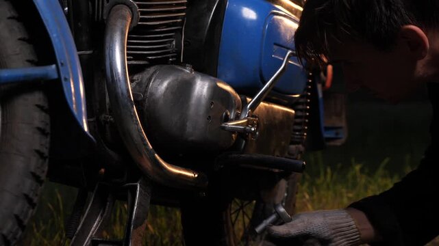 Mechanic repairing vintage motorcycle engine in the field