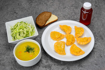 set of fried dumplings, salad and soup in a white plate