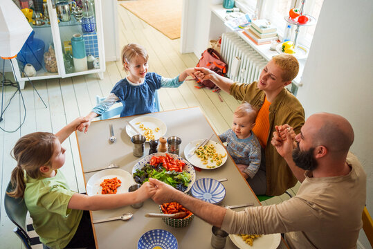 Family praying with each other before lunch at dining table