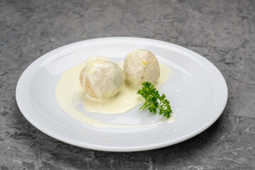 Chicken meatballs in creamy sauce in a white plate on a gray background