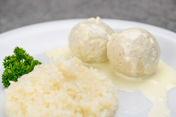 white rice with meatballs in a white plate on a gray background macro