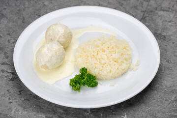 white rice with meatballs in a white plate on a gray background