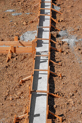 A building foundation with wooden formwork filled with fresh concrete is shown on a construction...