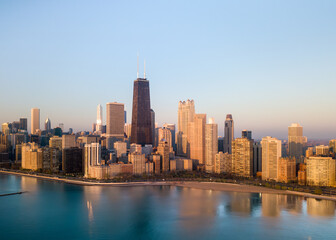 Aerial view of the dazzling skyline with the iconic John Hancock Center piercing the sky, reflected in the serene waters of Lake Michigan, Chicago, Illinois, United States.