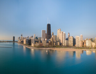 Aerial view of the iconic John Hancock Center and other skyscrapers cast long shadows over the turquoise lakefront, Chicago, Illinois, United States.