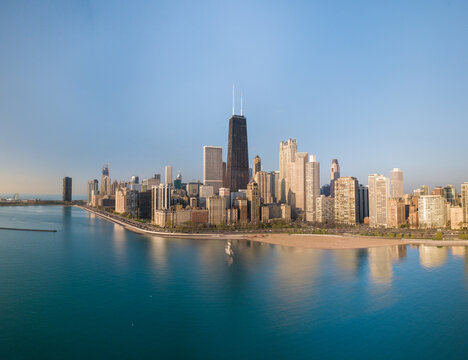 Aerial view of the iconic John Hancock Center and other skyscrapers cast long shadows over the turquoise lakefront, Chicago, Illinois, United States.