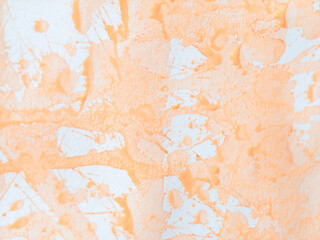 Fototapeta premium Light orange watercolor wash and splatters on textured white paper. Paint forms several elongated fluid streaks that run diagonally across. Small isolated splatters and drips are scattered