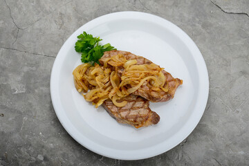 two steaks with onions in a white plate on a gray background