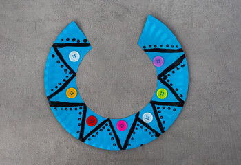 Blue paper plate with a pattern and buttons.