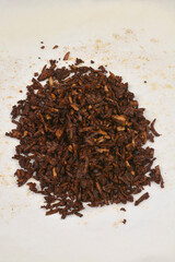 A pile of baked grated smoked tofu in a soy and mustard marinade is on baking paper, photographed from above