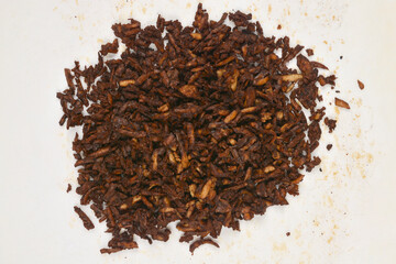 A pile of baked grated smoked tofu in a soy and mustard marinade is on baking paper, photographed from above