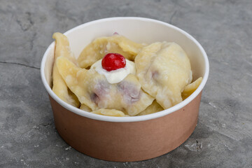 Dumplings with cherries and sour cream in disposable containers
