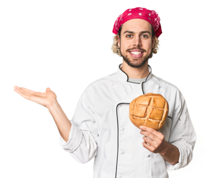 Young chef with artisan bread in studio showing a copy space on a palm and holding another hand on waist. - Powered by Adobe