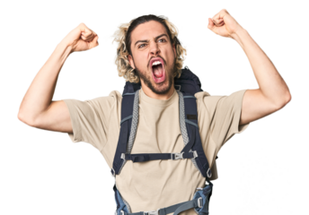 Young Caucasian hiker with backpack raising fist after a victory, winner concept.