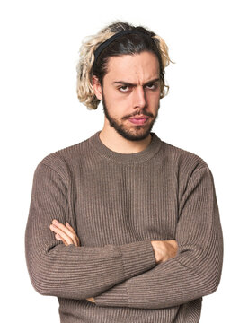 Young Caucasian man in studio setting suspicious, uncertain, examining you.
