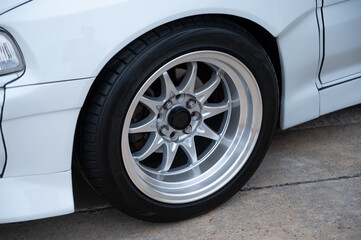 Detail of a multi-spoke alloy front wheel on a modified classic Japanese sports car, showcasing the clean, polished finish and aftermarket widebody modifications.