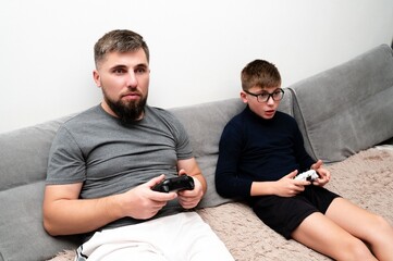 Fototapeta premium Father and son share exciting gaming moments on a cozy sofa as they immerse themselves in their favorite video game on a casual weekend afternoon