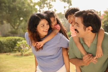 Fototapeta premium Carefree Parents And Their Small Kids Having Fun In The Park