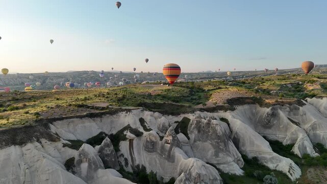 Hot air balloons float over Cappadocia's rocky landscape at sunrise