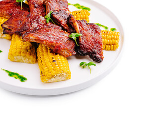 Grilled ribs served with corn on a white plate for a savory meal