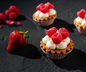 Delicious raspberry tartlets on a dark textured surface